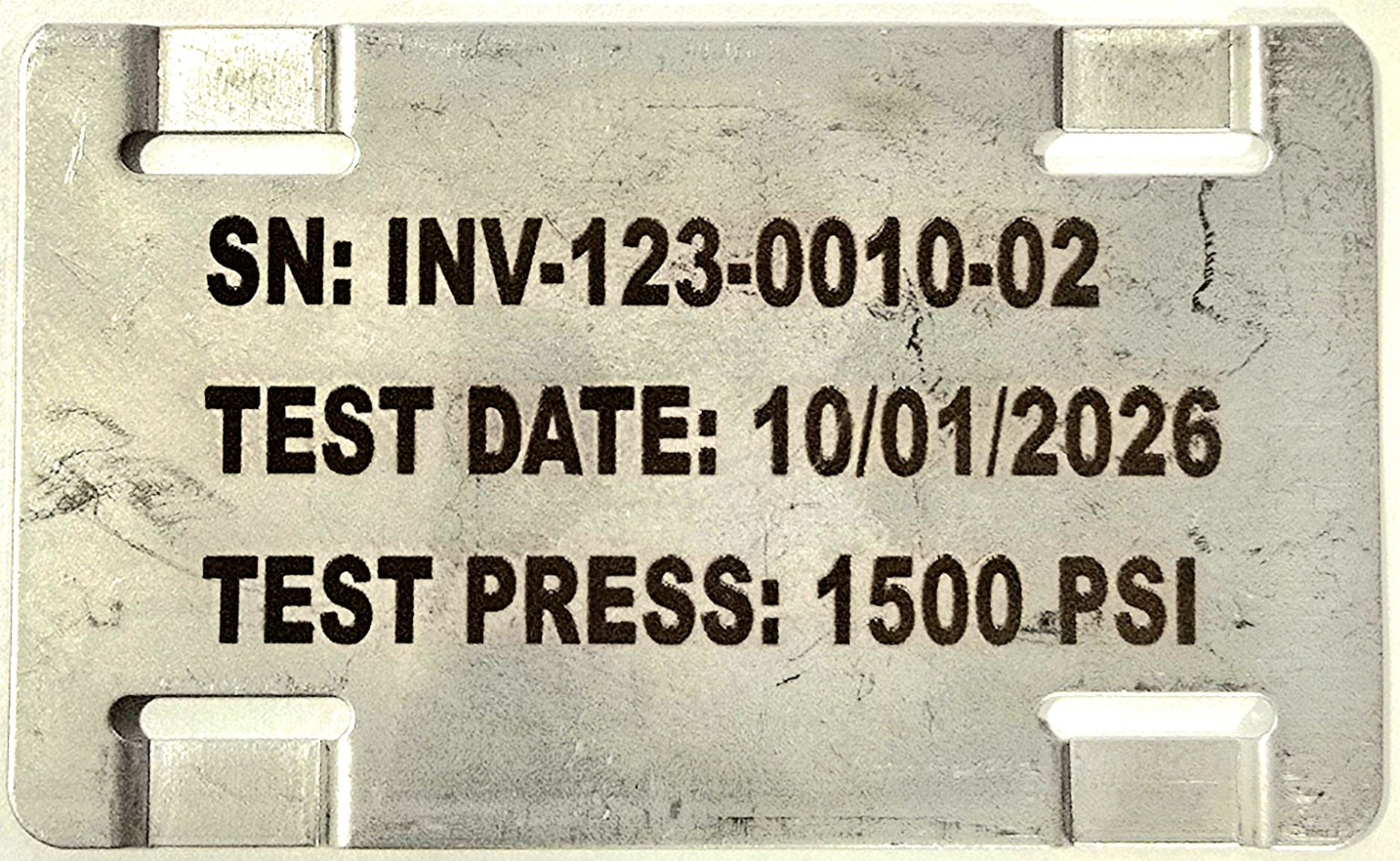 Example stainless identification tag showing assembly ID INV-123-0010-02, test date, and 1500 PSI test pressure